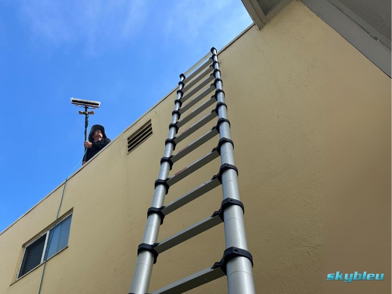 Skybleu technician cleaning windows on a high building with professional equipment in the San Francisco Bay Area.