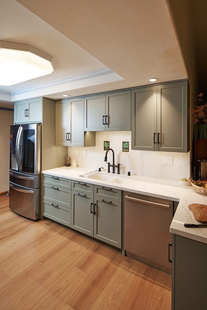 Green shaker cabinets with quartz countertops and a full-height slab backsplash in a Menlo Park kitchen remodel