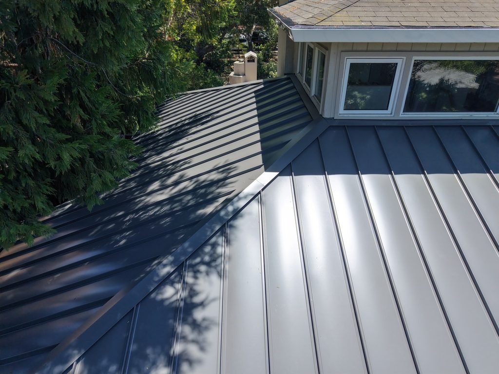 Close aerial view of raised standing seams meeting at a roof valley on charcoal metal panels
